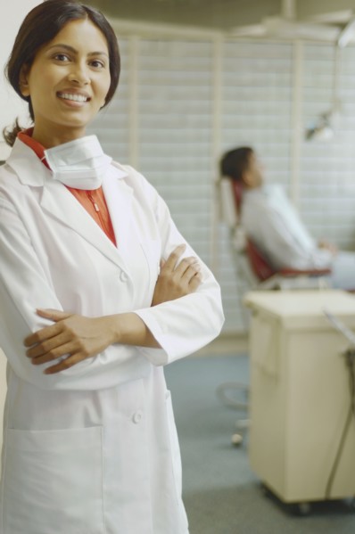 Indian female dentist smiling with patient in background