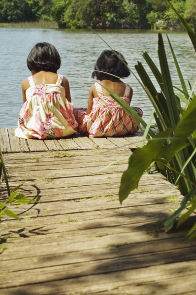 Indian girls sitting on dock over lake