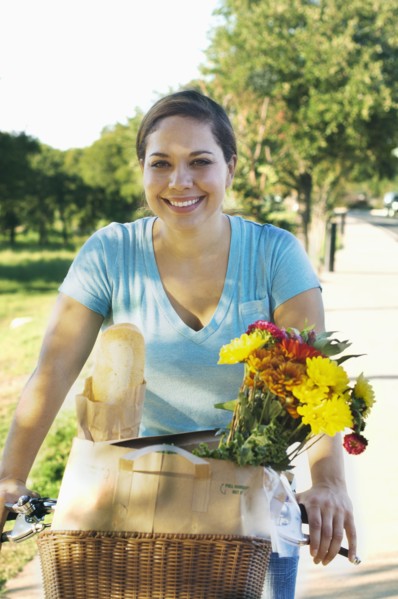 Mixed race woman riding bicycle with flowers in basket