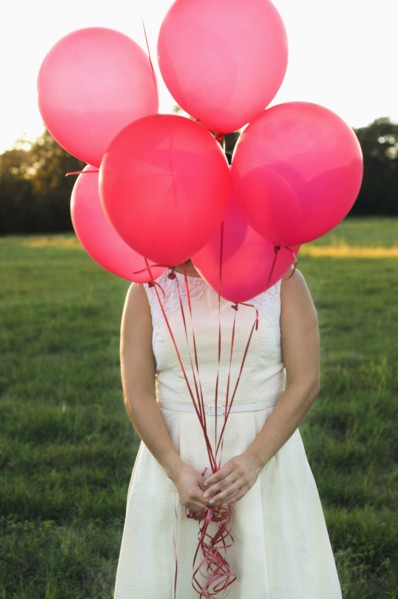 Mixed race woman with pink balloons in park