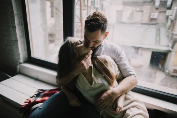 Caucasian couple kissing on window sill