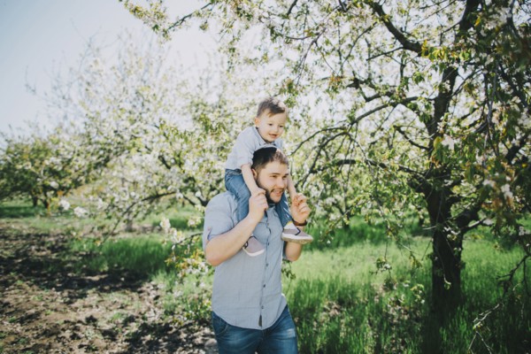 Caucasian father and son walking near tree