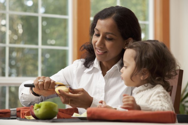Indian woman slicing apple for daughter