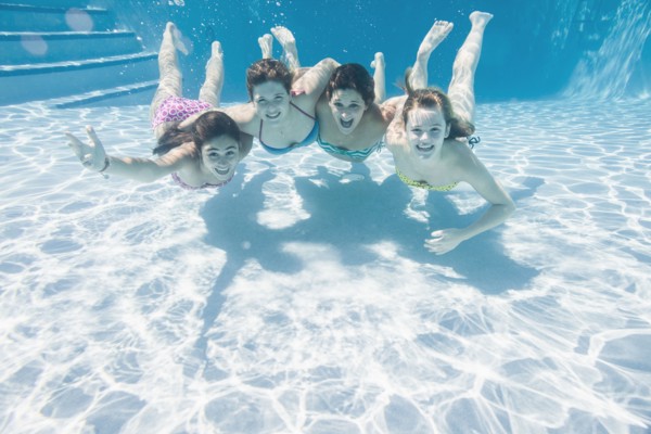 Smiling Caucasian teenagers underwater in swimming pool