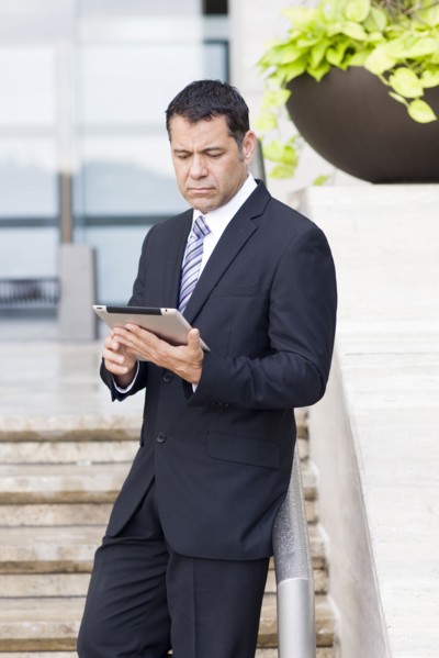 Hispanic businessman with tablet computer on city street