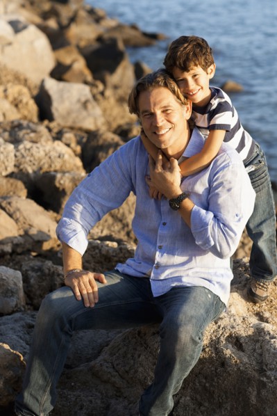 Caucasian father and son hugging on rocky beach