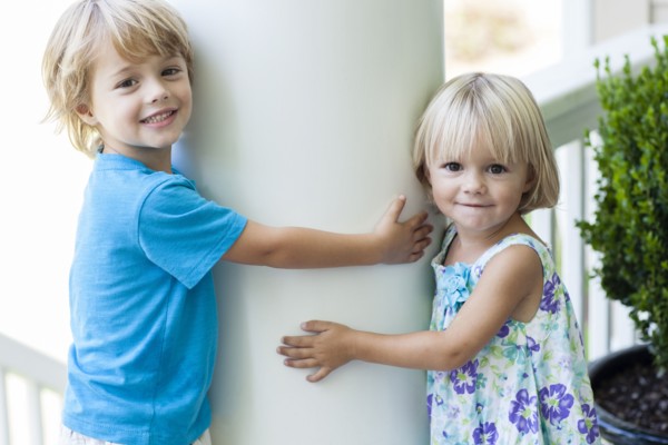 Caucasian children hugging column outdoors