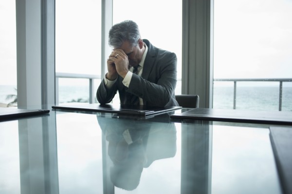Caucasian businessman holding head in hands at conference table