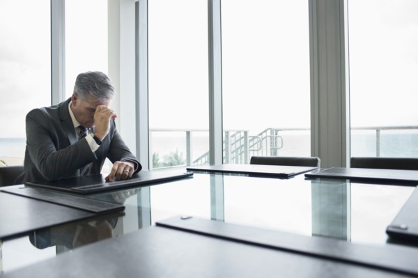 Caucasian businessman brooding at empty conference table