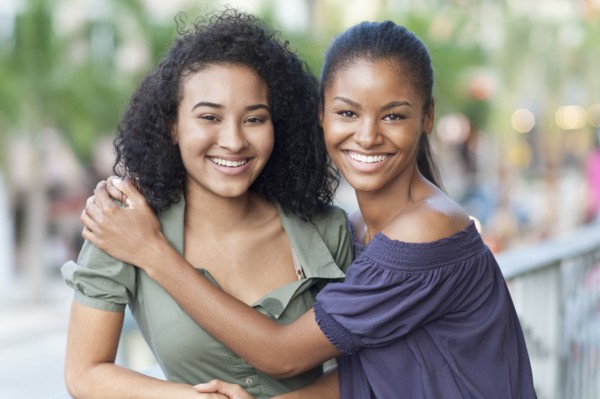 Black women hugging on balcony