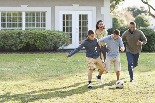 Family playing soccer in backyard