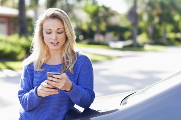 Caucasian woman using cell phone outside car