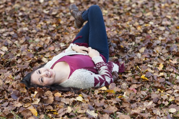 Hispanic teenage girl laying in autumn leaves