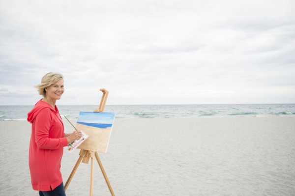 Older Caucasian woman painting on beach