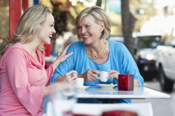 Caucasian mother and daughter drinking coffee at sidewalk cafe