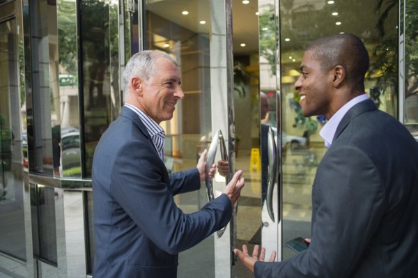 Businessman opening office door for colleague
