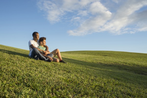 Father and son sitting in grass