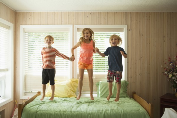 Caucasian children jumping on bed