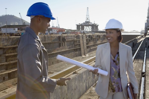 African American businesswoman and construction worker with blueprints