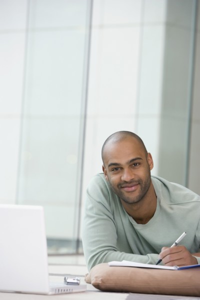 African man writing on notepad