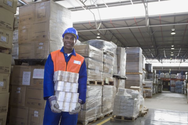 African worker carrying package in warehouse
