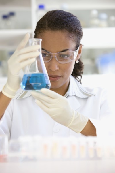 African scientist holding beaker of liquid in laboratory