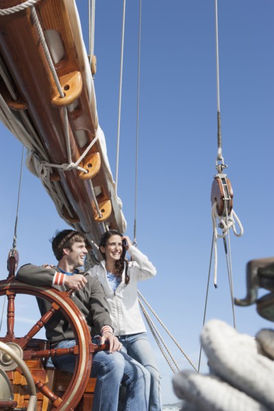 Caucasian couple at helm of sailboat