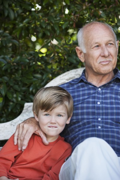 Caucasian boy sitting with grandfather on bench