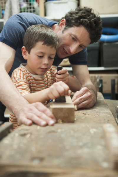 Caucasian father and son working in woodshop
