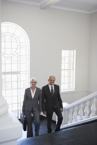 Senior Caucasian business people climbing office steps