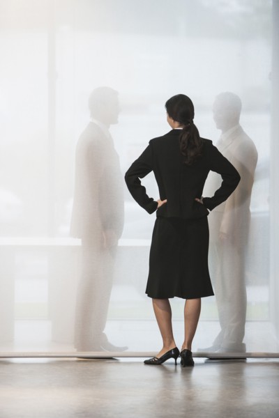 Businesswoman watching colleagues shake hands behind curtain