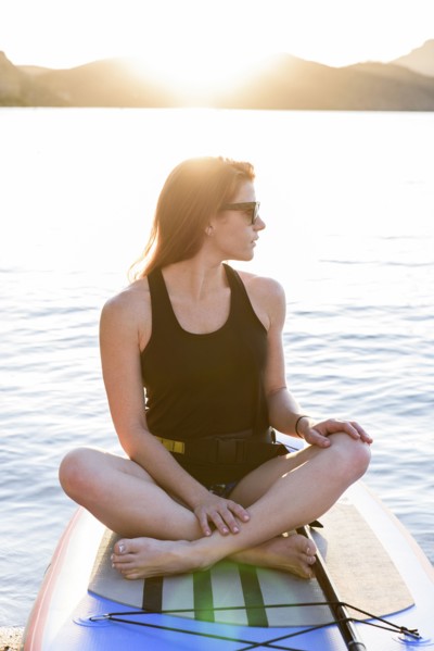 Caucasian woman sitting on paddleboard in river