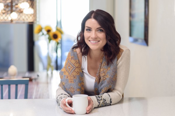 Caucasian woman leaning on counter drinking coffee