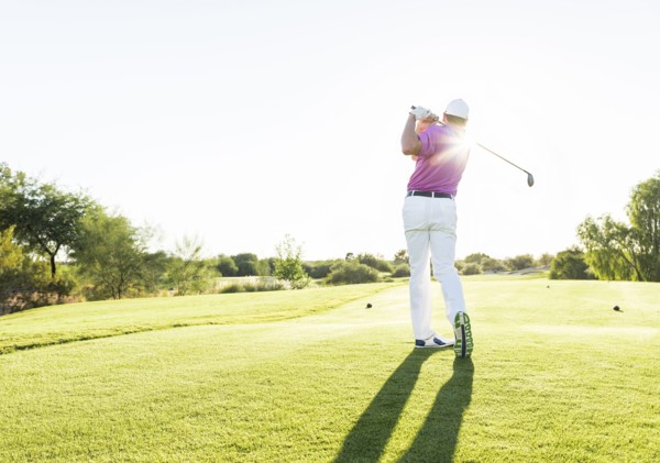 Hispanic golfer teeing off on golf course