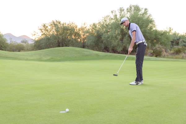Caucasian golfer putting on golf course