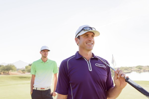 Friends holding golf clubs on golf course