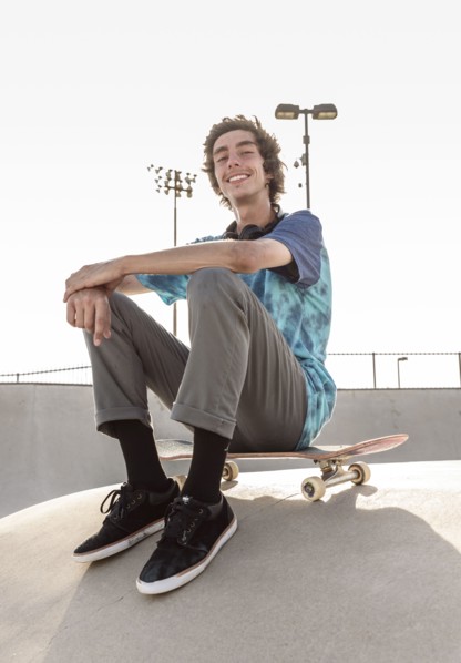 Portrait of smiling Hispanic man sitting on skateboard