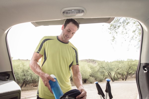 Hispanic man pulling water bottle from backpack in car