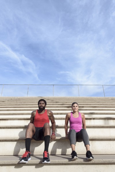 Man and woman doing triceps dips on bleachers