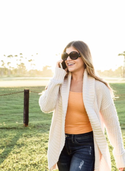 Smiling Hispanic woman wearing sunglasses talking on cell phone