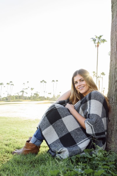 Hispanic woman leaning on tree
