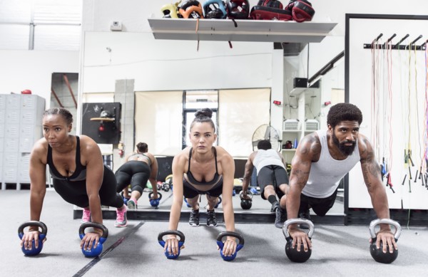 Man and women doing push-ups with kettlebells