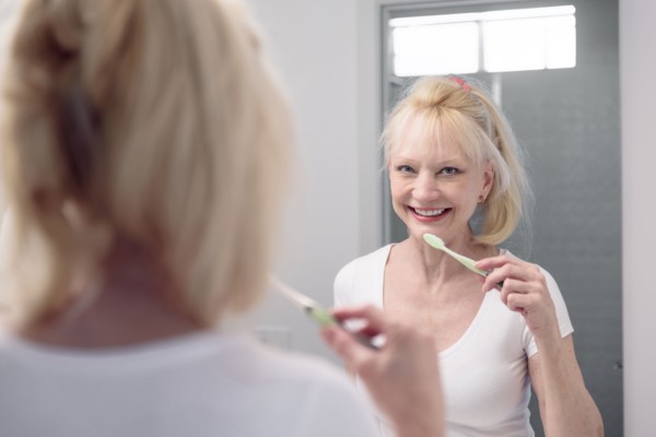 Caucasian woman brushing teeth in mirror