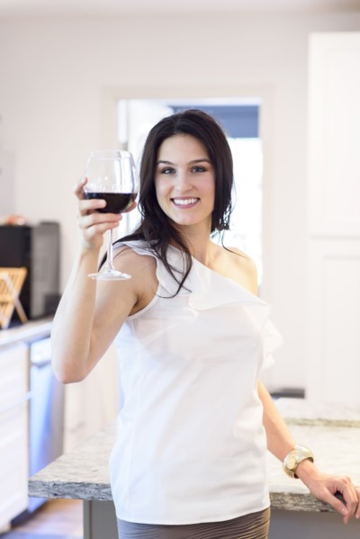 Smiling Caucasian woman toasting with red wine