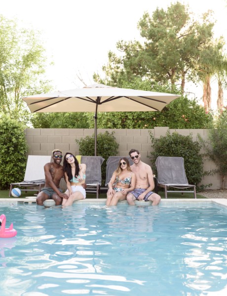 Smiling friends sitting and relaxing poolside