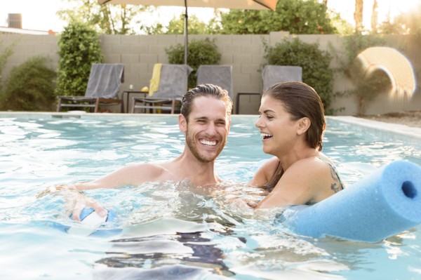 Smiling Caucasian couple relaxing in swimming pool