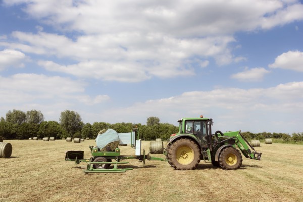 Caucasian man driving tractor baling hay