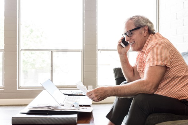 Smiling and Caucasian man sitting on sofa talking on cell phone