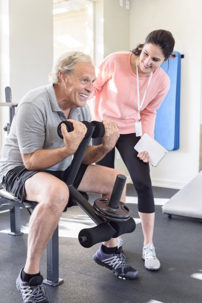 Caucasian trainer watching man strengthen arms