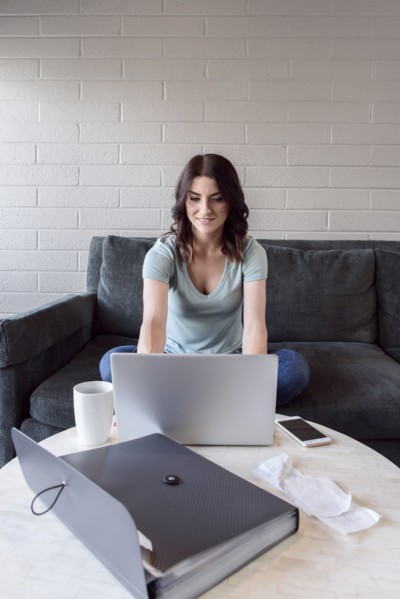 Caucasian woman sitting on sofa using laptop